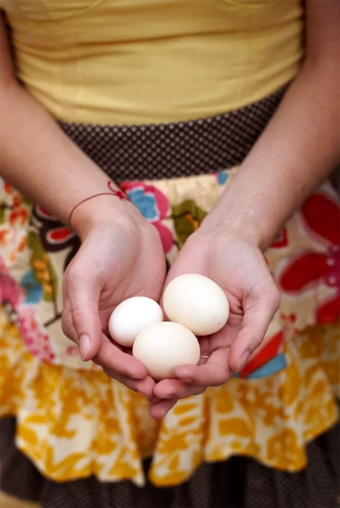 жінка тримає три свіжі яйця